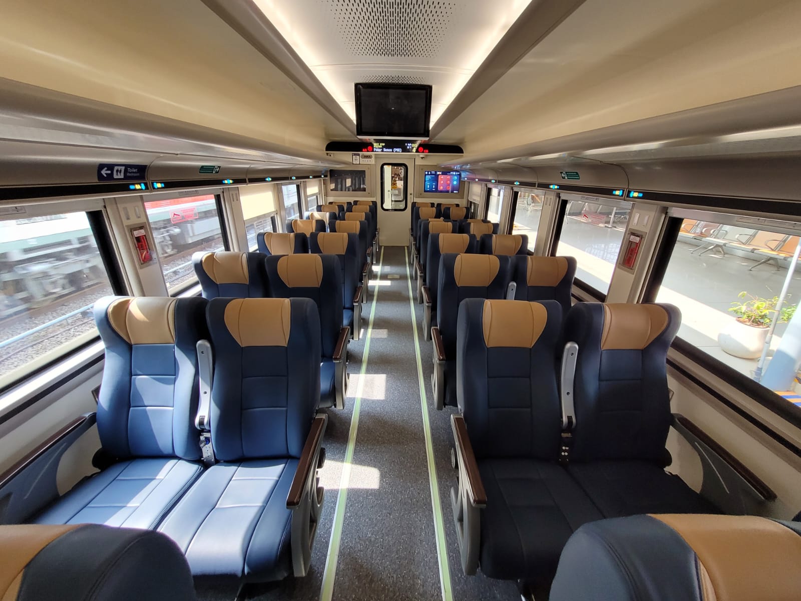 Interior kereta Ekonomi New Generation dengan kursi warna biru dua nada.
